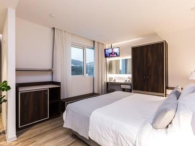 Modernes Hotelzimmer mit großem Bett, Flachbildfernseher und Fenster mit Blick nach draußen.