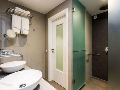 Modernes Badezimmer mit Doppelwaschbecken, Handtüchern und Glasdusche.