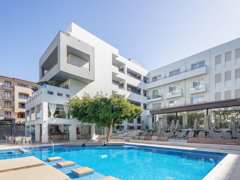 Moderner Hotelkomplex mit klarem blauen Pool und Sitzbereich unter hellem Himmel.