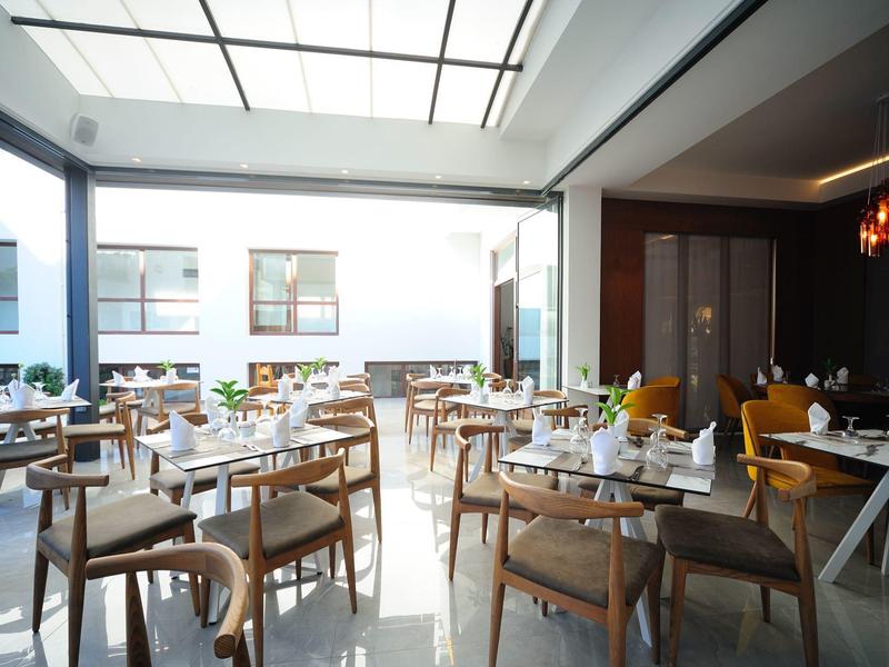 Hell eingerichtetes Café mit Holztischen, Stühlen und großen Fenstern für viel Tageslicht.