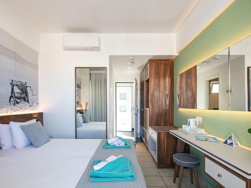 Modernes Hotelzimmer mit Doppelbett, großen Spiegeln, Holzmöbeln und grünem Akzentlicht.