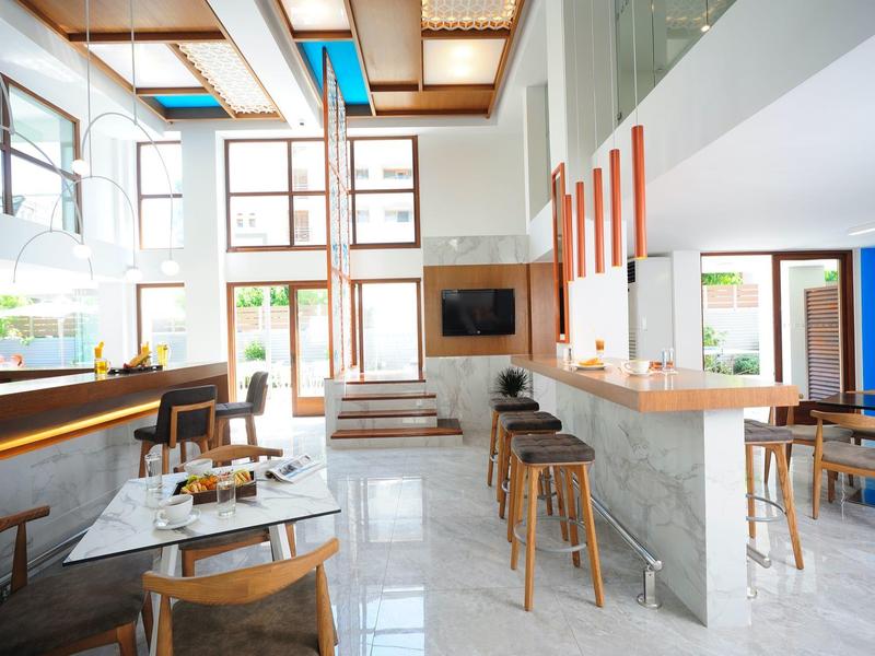 Heller, moderner Gastraum mit Holzstühlen, hohen Fenstern und minimalistischer Bartheke.