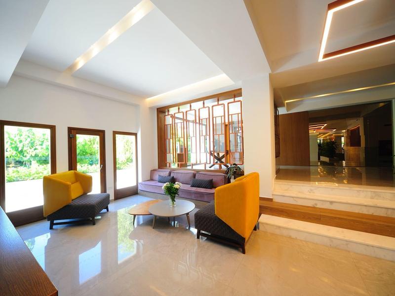 Modernes Wohnzimmer mit großen Fenstern, beigen Fliesen, gelben Sesseln und einem Glas-Couchtisch.