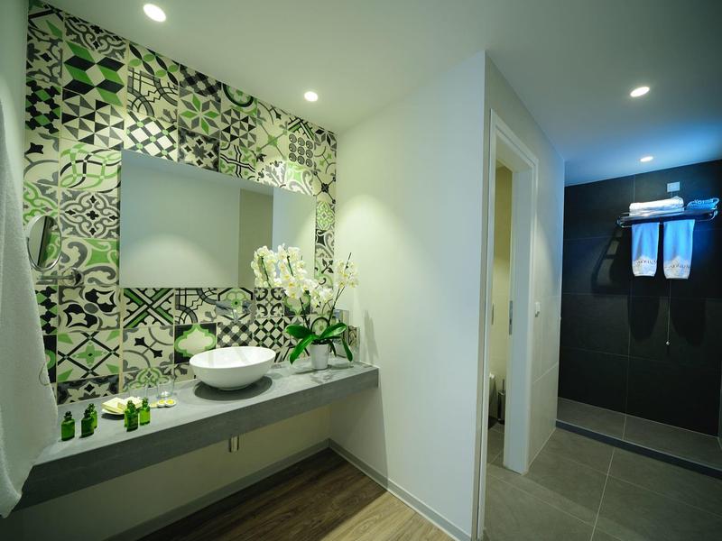 Modernes Badezimmer mit gemusterten Fliesen, weißem Waschbecken und dunkler Duschkabine.