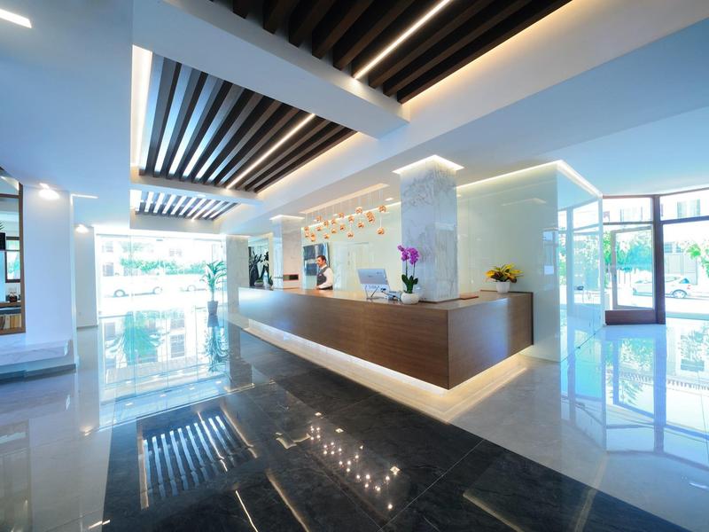Heller Empfangsbereich mit modernem Holztheken, glänzendem Boden und großen Fenstern.