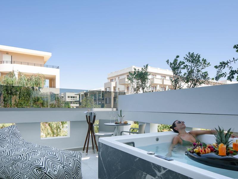 Moderner Balkon mit Whirlpool, Liegestuhl, Pflanzen und klarem blauen Himmel im Hintergrund.
