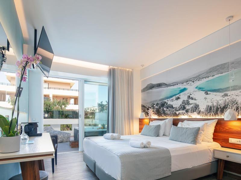 Modernes Hotelzimmer mit zwei Betten, Balkon, Schreibtisch und großem Bild über dem Bett.