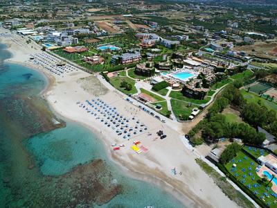 Luftaufnahme eines Strandes mit Liegestühlen, Hotels und klarem blauem Wasser an der Küste.