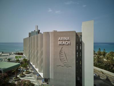 Edificio di hotel moderno sulla spiaggia con vista mare e palme sullo sfondo.