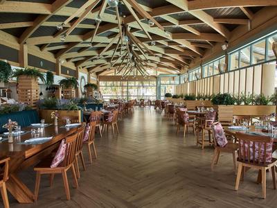 Ampia sala da pranzo moderna con pavimento in legno e molti tavoli in un hotel.