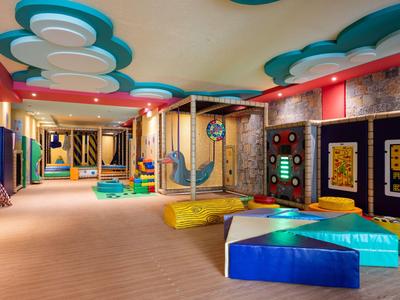 Area giochi interna moderna e colorata con tappeti morbidi e attrezzature da arrampicata in un hotel.