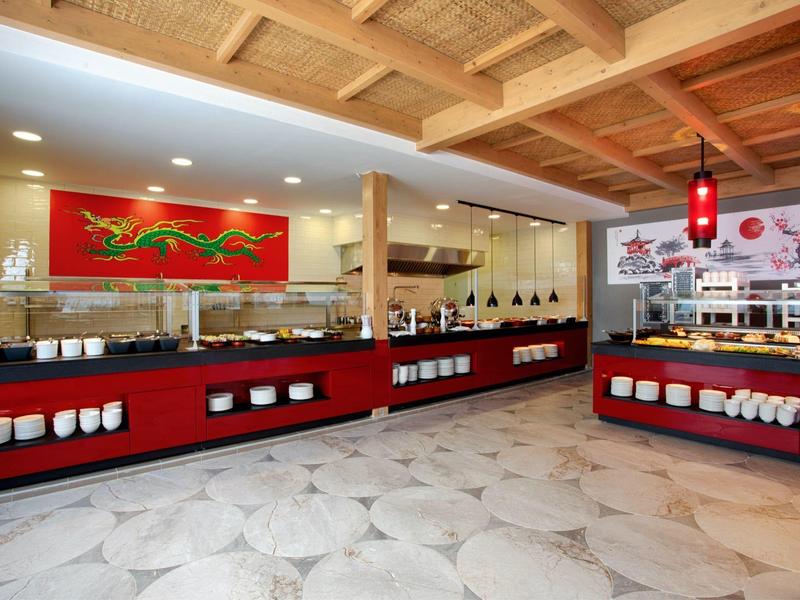 Moderní bufet s červeným dekorem, dřevěným stropem a geometrickou podlahou.