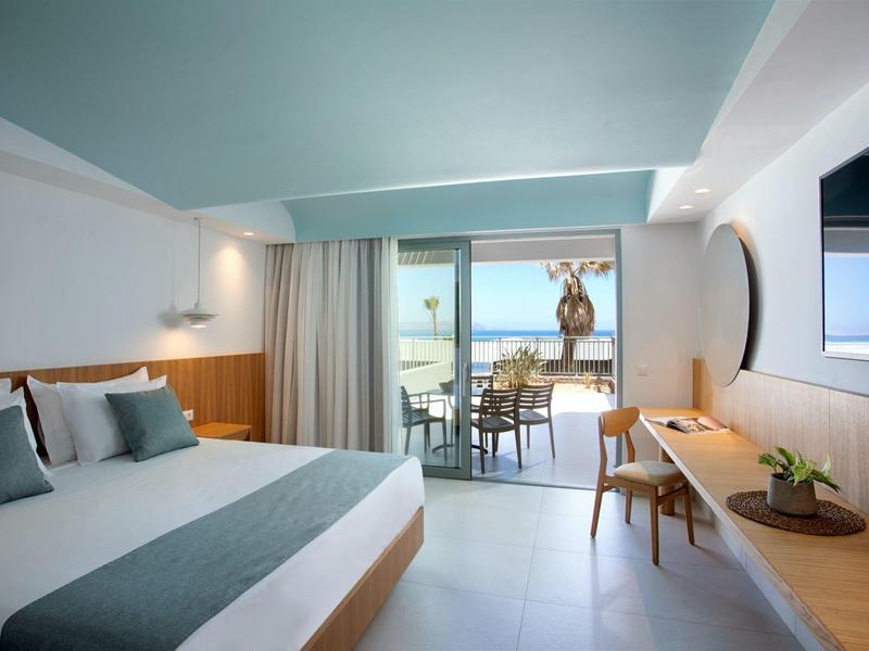 Moderní hotelový pokoj s postelí, terasou a výhledem na moře.