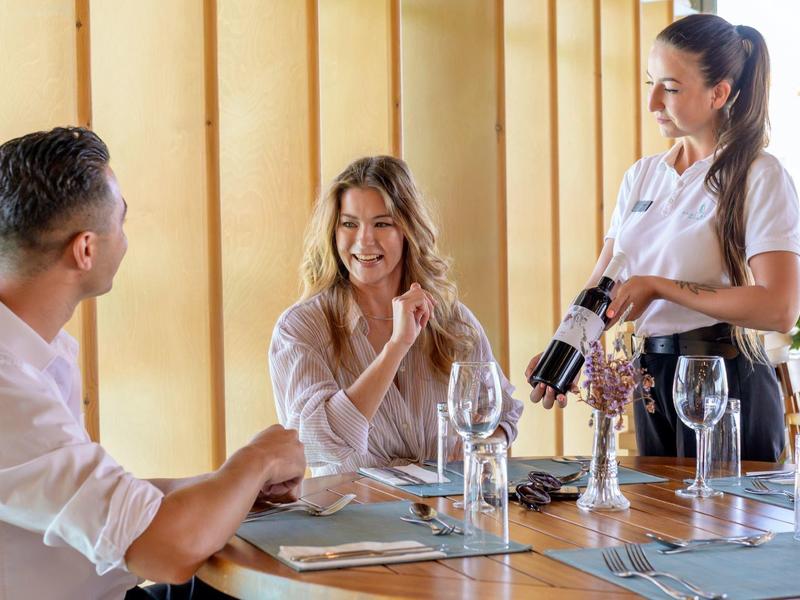 Pár se usmívá a mluví s usměvavou číšnicí v elegantní restauraci.