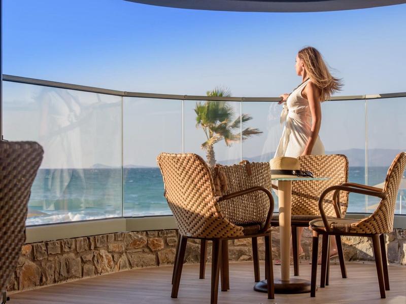 Hotelová terasa s výhledem na moře a žena obdivující krajinu.