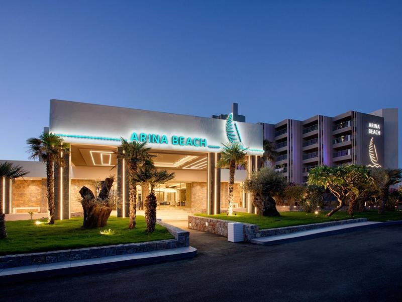 Moderní hotel osvětlený za soumraku s osvětleným vchodem a tropickou vegetací.