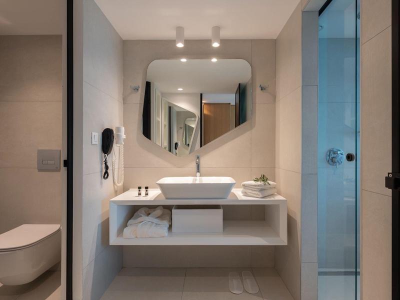 Moderní koupelna se umyvadlem, zrcadlem, toaletou a skleněným sprchovým koutem.