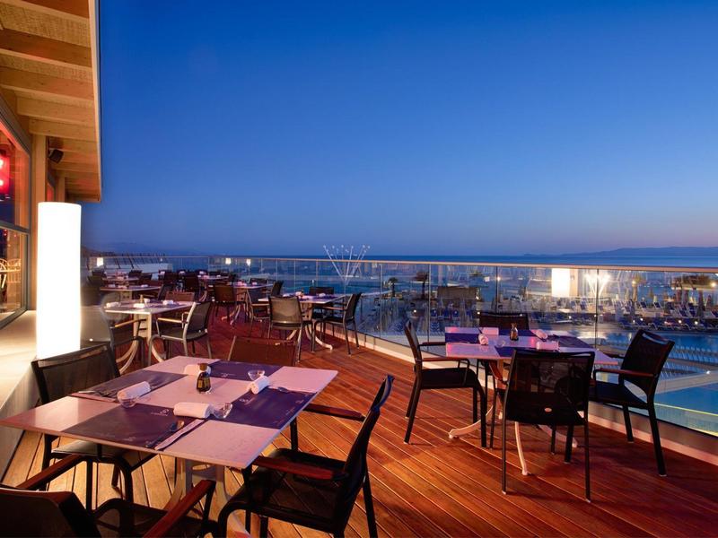 Terasa restaurace s výhledem na přístav při soumraku, připravené stoly.