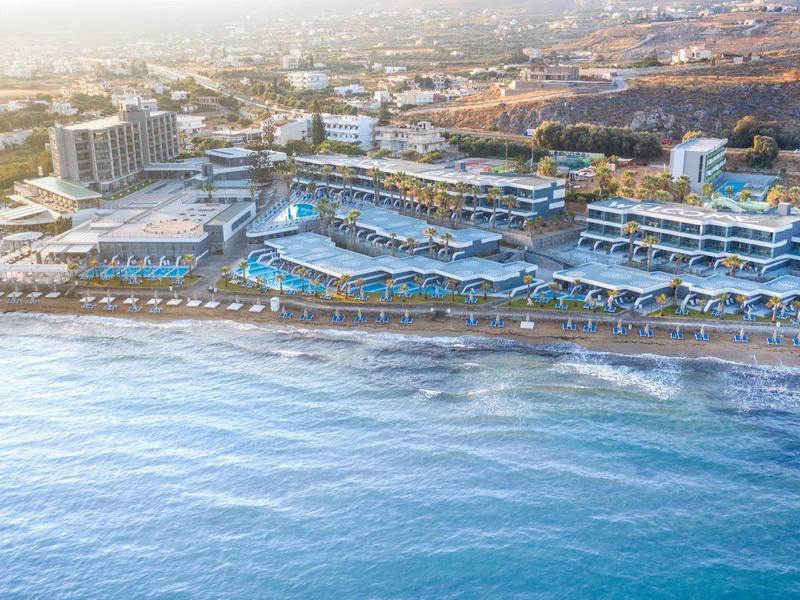 Letecký pohled na moderní hotel u moře s bazénem a soukromou pláží.