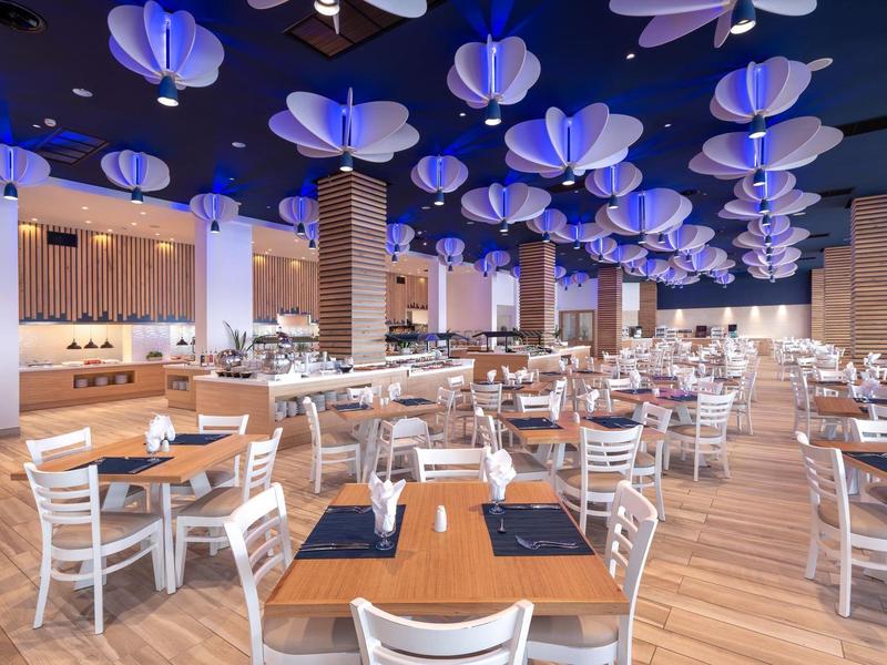 Prostorná moderní restaurace s modrými lucernami zavěšenými na stropě.