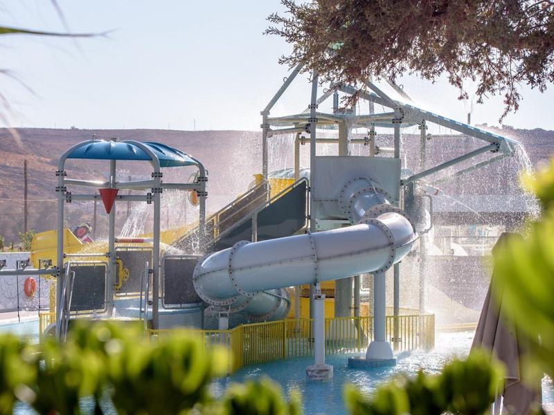 Vodní hřiště s tubusem skluzavky a slunečníkem v slunném prostředí.