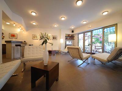 Jasna lobby hotelowa z nowoczesnymi fotelami, sofami, stołem i dużymi oknami z widokiem na taras.