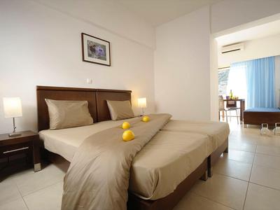 Nowoczesny pokój hotelowy z dwoma łóżkami, stolikami nocnymi i otwartym dostępem do salonu.