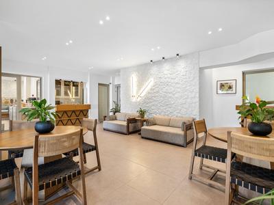 Área de estar y comedor amueblada de forma moderna con mesas, sillas y sofás en una habitación luminosa.