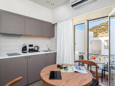 Mała nowoczesna aneks kuchenny z okrągłym drewnianym stołem i dostępem do balkonu z widokiem na wzgórza.