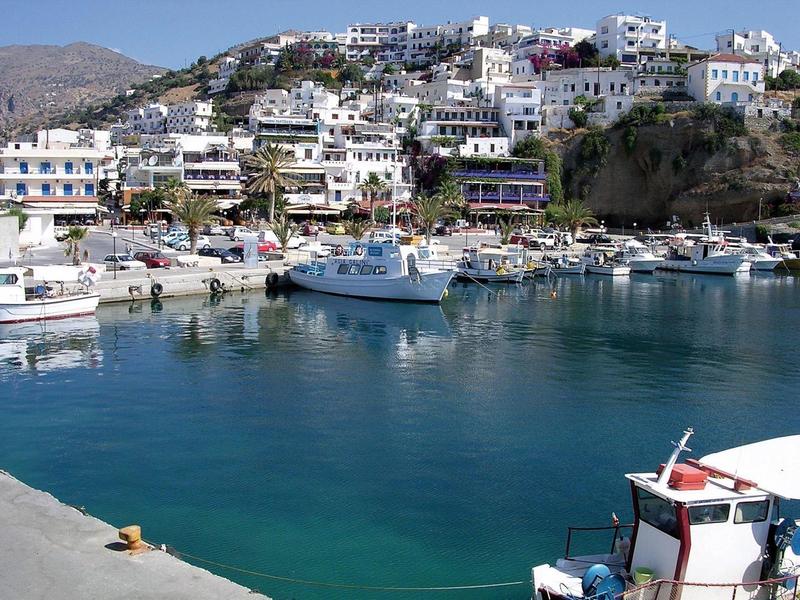 Port z łodziami i białymi domami na słonecznym wzgórzu w miejscu wakacyjnym.