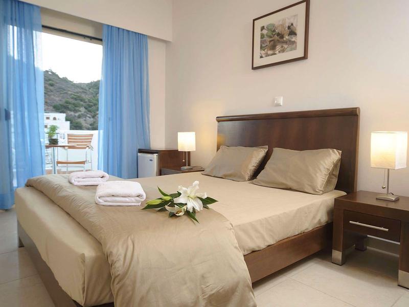 Nowoczesna sypialnia z podwójnym łóżkiem, stolikami nocnymi, lampami i niebieskimi zasłonami.