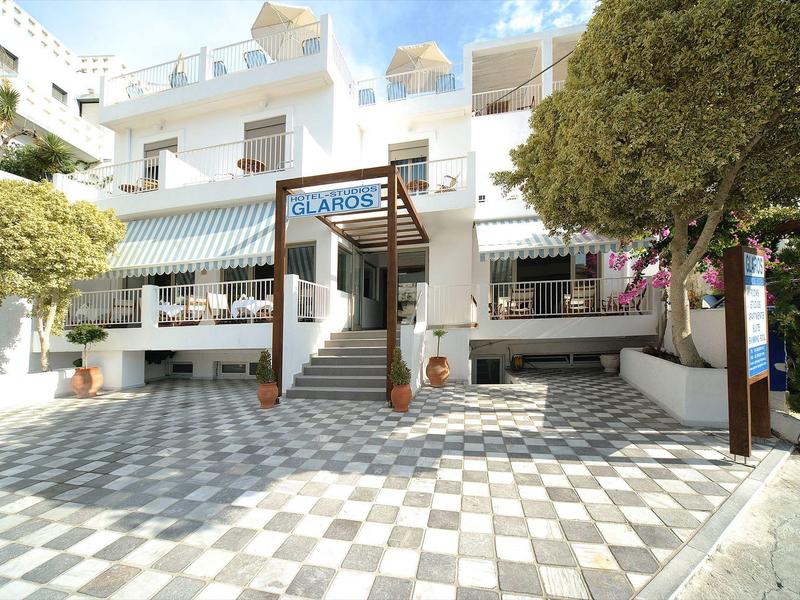 Wejście do hotelu z białym budynkiem, drzewami i szachownicowym wzorem podłogi.