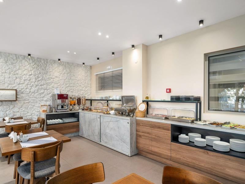 Nowoczesny kącik śniadaniowy z ekspresem do kawy, wyborem pieczywa i miejscami do siedzenia w jasnym pomieszczeniu.