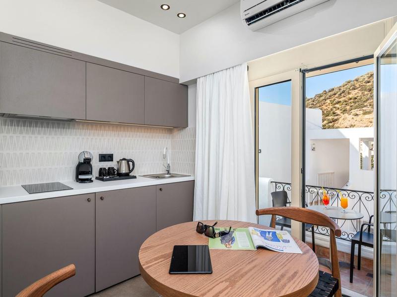 Mała nowoczesna aneks kuchenny z okrągłym drewnianym stołem i dostępem do balkonu z widokiem na wzgórza.