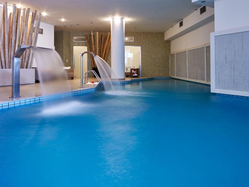 Piscine intérieure avec jets d'eau et décoration moderne dans un hôtel ou spa.
