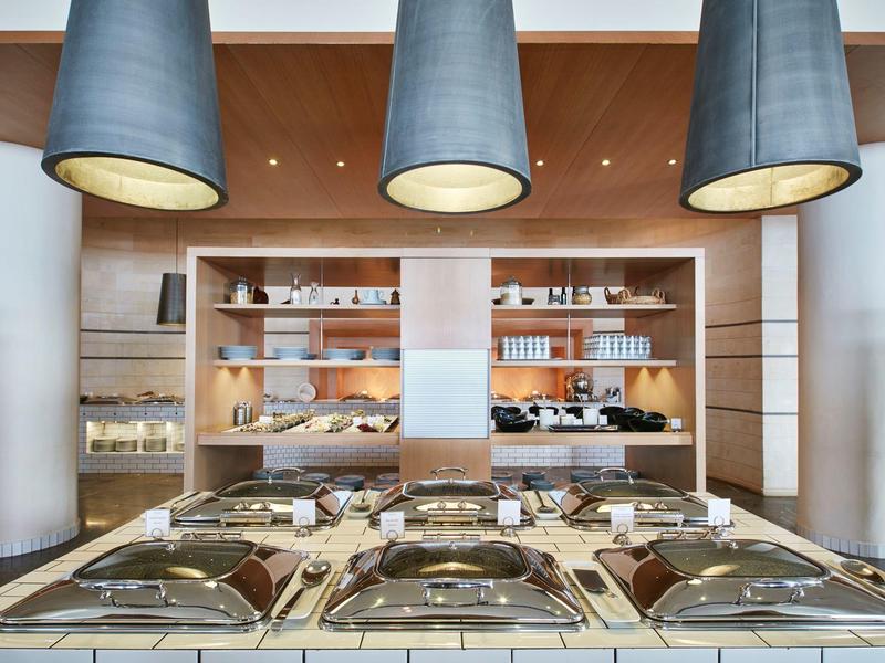 Buffet avec plateaux couverts et étagères d'articles de petit-déjeuner sous trois grandes suspensions.