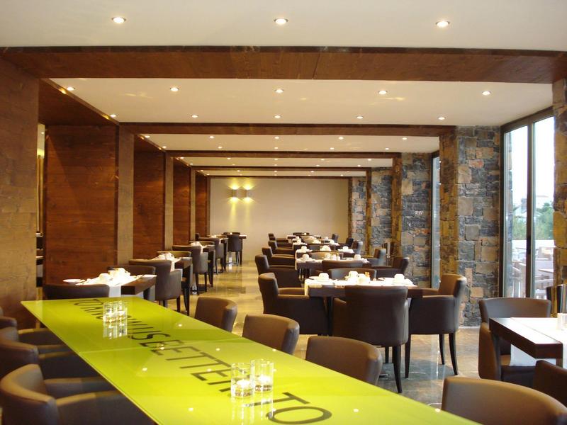 Restaurant d'hôtel spacieux avec chaises foncées, murs en bois et grande table vert citron.