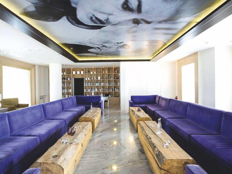 Salon luxueux avec canapés bleu profond et tables basses en bois, lumière naturelle éclatante.