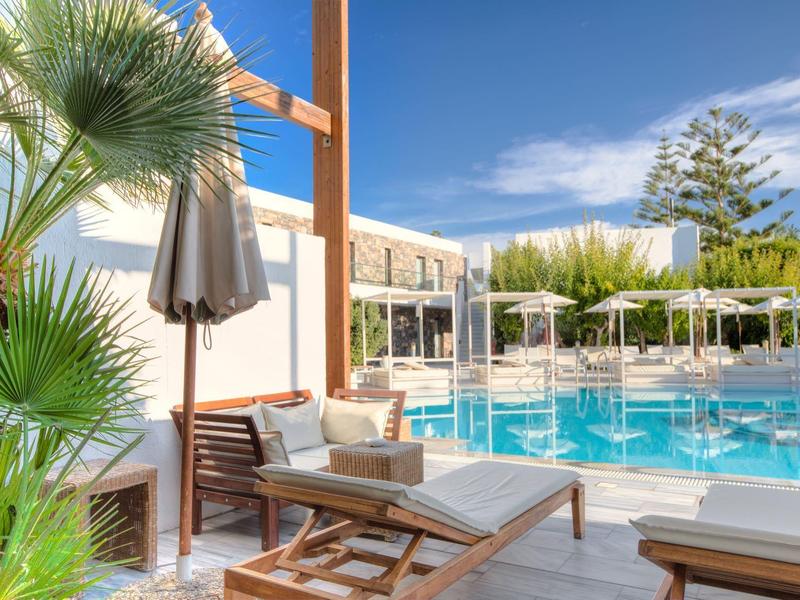 Terrasse ensoleillée avec chaises longues et piscine entourée de verdure sous un ciel bleu