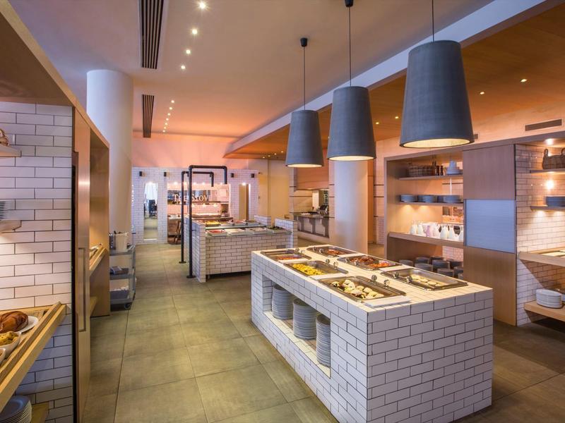 Espace buffet d'hôtel moderne avec éclairage chaleureux et comptoir central pour la présentation des plats.