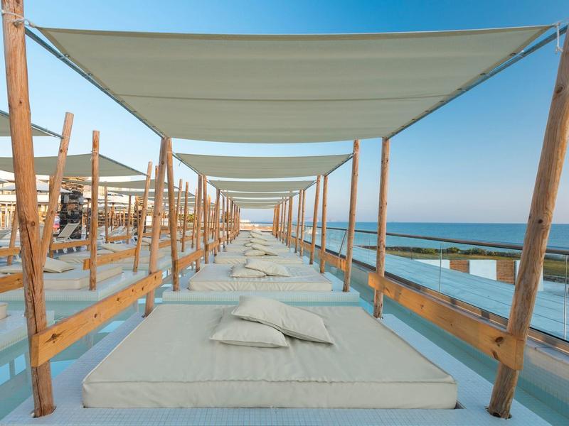 Lits de plage avec coussins sous des auvents au bord de la mer par une journée ensoleillée