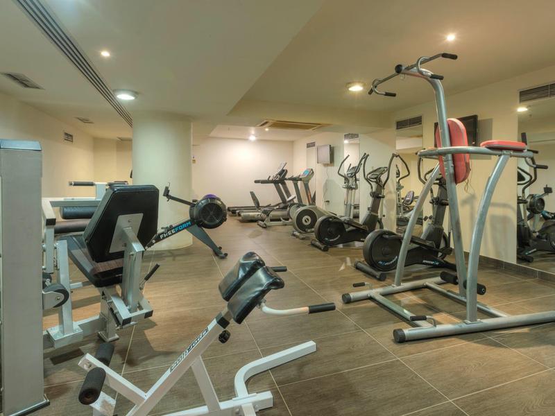 Salle de sport moderne d'hôtel avec divers appareils de fitness et un éclairage adéquat.