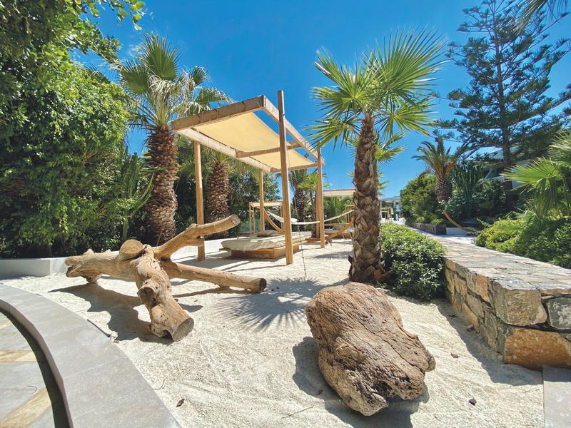Espace extérieur de style plage avec structures en bois et palmiers sous un ciel clair.