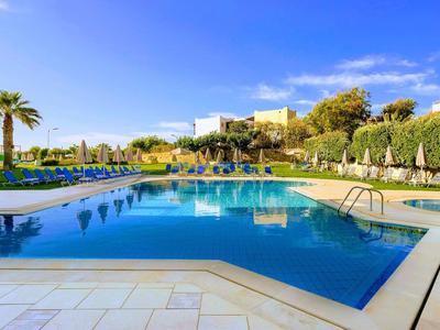 Czysty niebieski basen z leżakami i palmami w słoneczną pogodę.