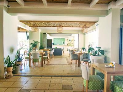 Světelné a útulné jídelní prostory s dřevěným nábytkem a mnoha rostlinami.