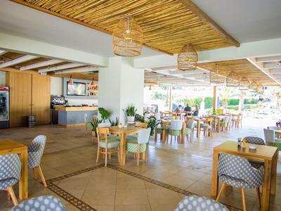 Prostorná světlá jídelna s dřevěným nábytkem a přírodním dřevěným stropem v hotelu.