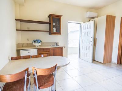 Světlá jídelna se stolem, čtyřmi židlemi a kuchyňským koutem v světlé místnosti.