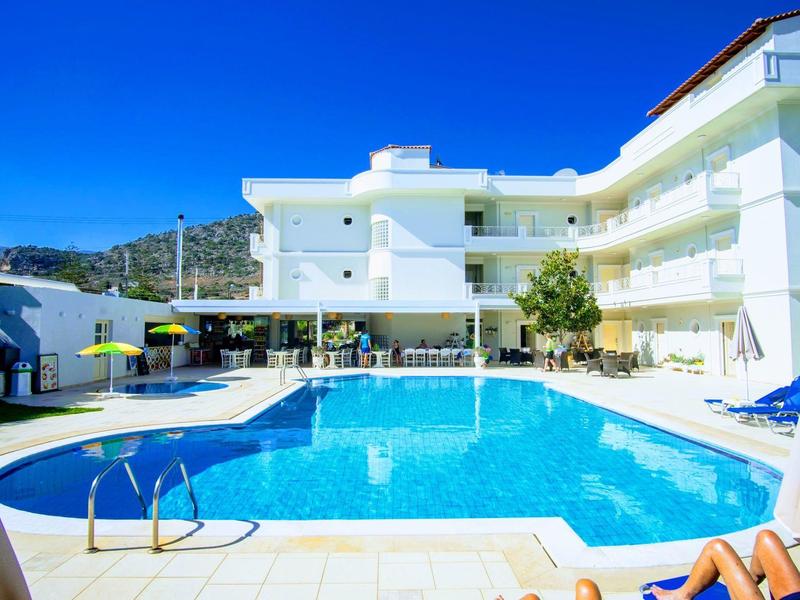 Moderní hotelový bazén s lehátky a modrou oblohou v pozadí.