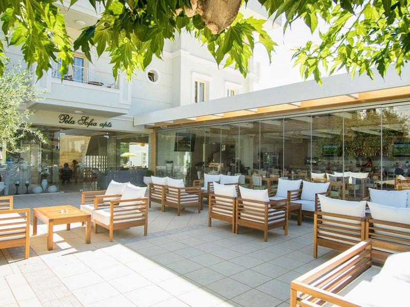 Venkovní restaurace s dřevěným nábytkem a zeleným baldachýnem v hotelu.