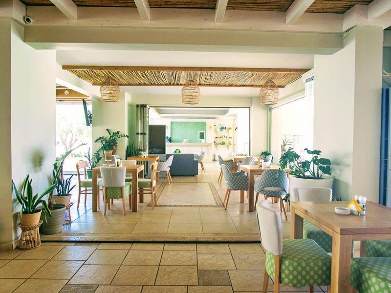 Světelné a útulné jídelní prostory s dřevěným nábytkem a mnoha rostlinami.